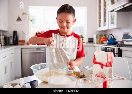 Pre-teen Boy einen Kuchen in der Küche mischen Backmischung, Lächeln, Nahaufnahme Stockfoto