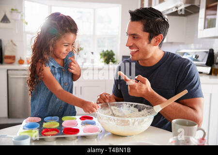 Junge Mädchen steht am Küchentisch Kuchen, mit ihrem Vater, Verkostung der Backmischung, Nahaufnahme Stockfoto