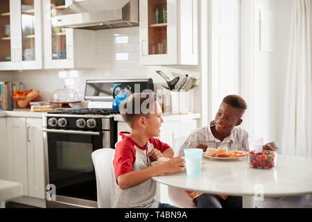 Zwei vor - jugendlich männliche Freunde sitzen im Gespräch in der Küche bei einem PLAYDATE an einem Boy's House Stockfoto