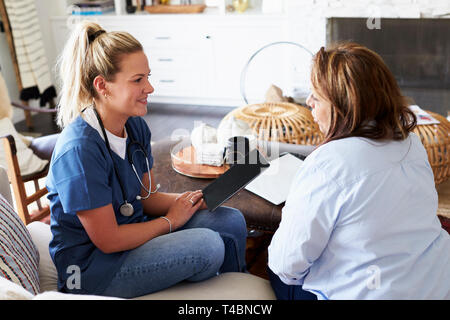 Weibliche healthcare Arbeiter auf dem Sofa sitzen mit einer Frau mittleren Alters während einer Home Gesundheit besuchen Sie Stockfoto