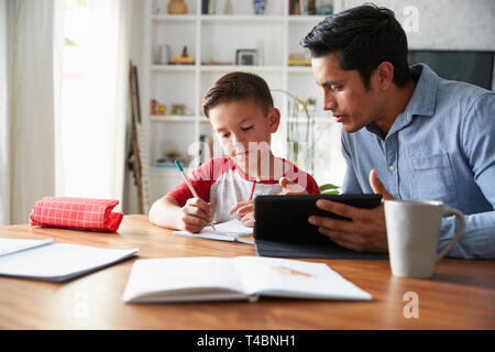 Spanischer pre-teen Boy am Esstisch arbeiten mit seinem Hause Schule tutor Sitzen Stockfoto