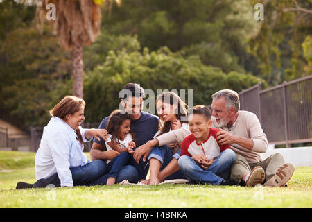 Gerne drei Generation spanischer Familie sitzt auf dem Rasen im Park, selektiven Fokus Stockfoto