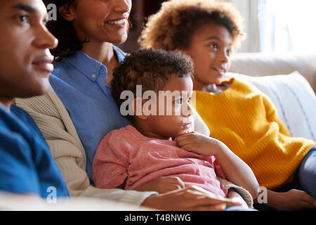 Nahaufnahme der Kinder sitzen auf dem Sofa im Wohnzimmer vor dem Fernseher mit ihren Eltern, Seitenansicht Stockfoto