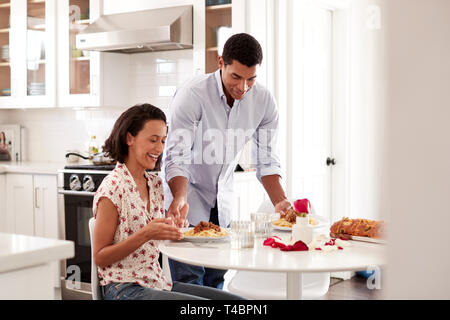 Junge erwachsene Frau am Tisch sitzen in der Küche und Ihren Partner mit einem romantischen Essen, selektiver Fokus Stockfoto