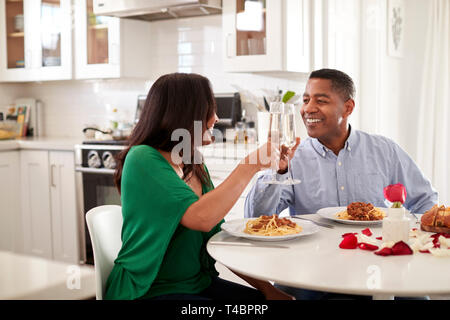 Mittleren Alters gemischten Rennen Paar einen Toast über ein romantisches Essen in Ihrer Küche, in der Nähe Stockfoto