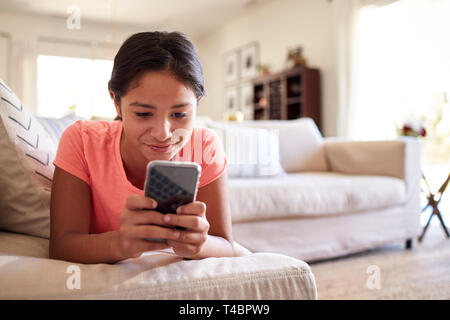 Teenager auf dem Sofa zu Hause im Wohnzimmer mit Smartphone, Nahaufnahme, niedrigen Winkel, in der Nähe Stockfoto