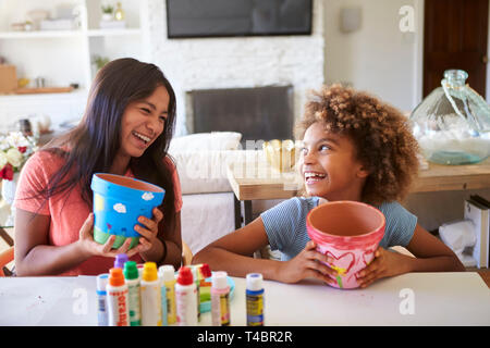 Glücklich vor - jugendlich Mädchen und ihre ältere Freundin, Blumentöpfe, dass Sie mit Farben zu Hause eingerichtet haben, einander an, Lächeln, Nahaufnahme Stockfoto