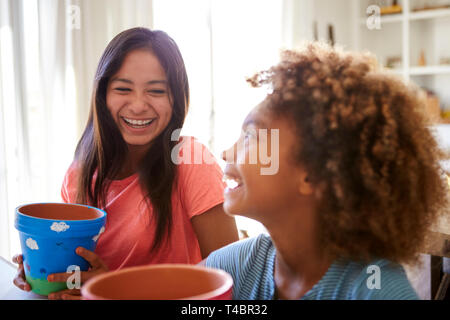 Lachend vor - jugendlich Mädchen und ihre ältere Freundin, Blumentöpfe, dass Sie mit Farben zu Hause, selektiven Fokus eingerichtet haben, in der Nähe Stockfoto