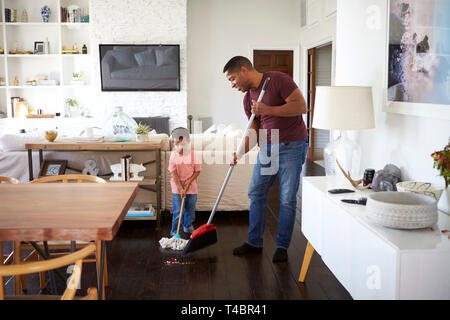 Großvater und seine drei Jahre alten Enkelsohn wischen und Fegen der Speisesaal, volle Länge Stockfoto