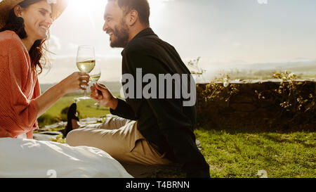 Nahaufnahme von ein romantisches Paar sitzen zusammen in einem Weingut holding Glas Weisswein. Glückliches Paar auf einem Datum Ausgabe Zeit zusammen reden und d Stockfoto
