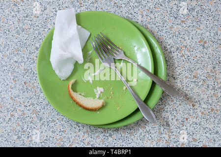 Grüne schmutzige Teller mit Resten. Auf dem Stein Küchenarbeitsplatte. Blick von oben. Stockfoto