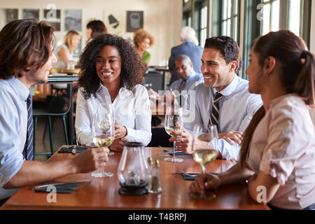 Kollegen um Tisch im Restaurant Wein trinken Sitzen Stockfoto