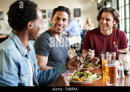 Gruppe von männlichen Freunden genießen Essen im Restaurant zusammen Stockfoto