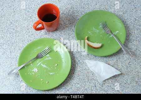 Grüne schmutzige Teller und eine Tasse mit den Resten der Küche. Auf dem Stein Küchenarbeitsplatte. Blick von oben. Stockfoto