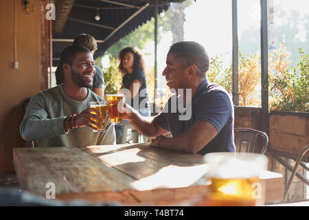 Zwei männliche Freunde treffen in Sports Bar, Toast zusammen Stockfoto