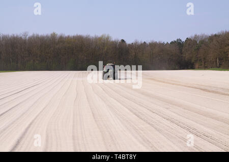 ROERMOND, Niederlande - 30 März. 2019: Chalk Düngung von Traktor mit Spreader das Feld für wachsenden Rasen vorbereiten Stockfoto