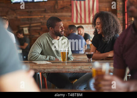 Junges Paar Treffen im Sport Bar mit Getränk vor dem Spiel Stockfoto