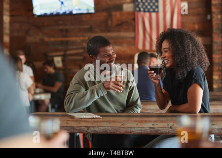 Junges Paar Treffen im Sport Bar mit Getränk vor dem Spiel Stockfoto