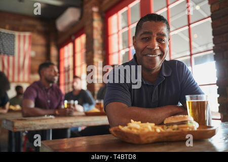 Porträt der Mann im Sport Bar Essen Burger und Pommes Frites Stockfoto