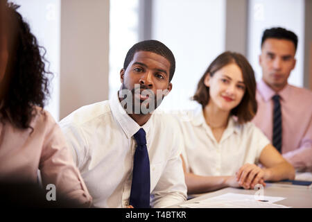 Gruppe von Unternehmern und Unternehmerinnen Sitzen am Tisch hören Präsentation in modernen Büro Stockfoto