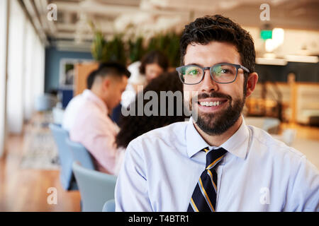Portrait von Geschäftsmann in modernen Büro mit Kollegen treffen um den Tisch im Hintergrund Stockfoto