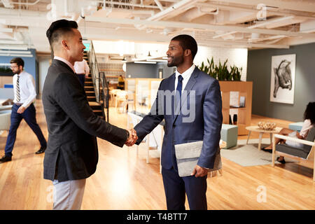 Zwei Geschäftsleute treffen und Händeschütteln In der modernen Großraumbüro Stockfoto