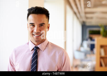 Portrait von lächelnden Reife Geschäftsmann in modernen Büro stehen, Fenster Stockfoto