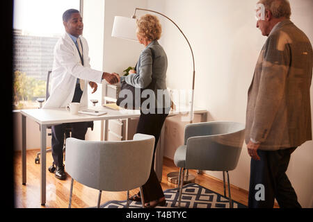 Senior Paar von männlicher Arzt mit Handshake auf Besuch im Krankenhaus für die Konsultation begrüßt Stockfoto