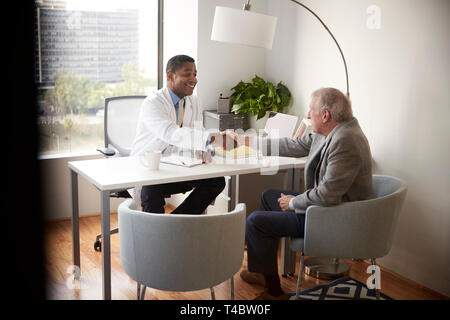 Ältere Menschen, begrüßt von männlichen Arzt mit Handshake auf Besuch im Krankenhaus für die Konsultation Stockfoto