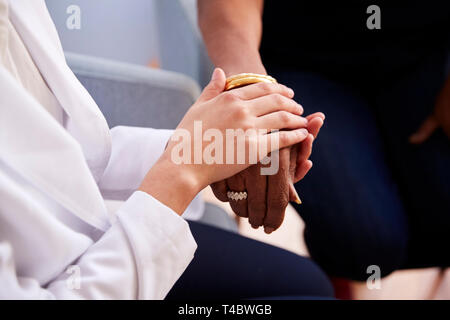 In der Nähe der weiblichen Arzt im Büro beruhigend Senior Frau Patienten und halten Ihre Hände Stockfoto
