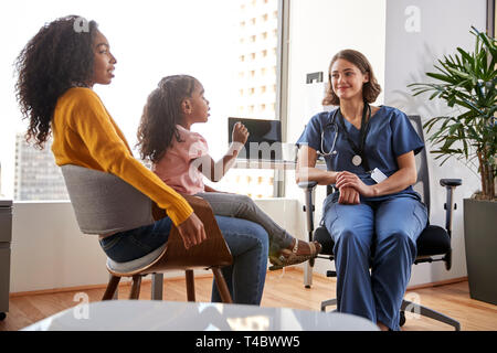 Mutter und Tochter in Absprache mit weiblichen Kinderarzt tragen Peelings im Krankenhaus Büro Stockfoto