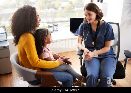 Mutter und Tochter in Absprache mit weiblichen Kinderarzt tragen Peelings im Krankenhaus Büro Stockfoto