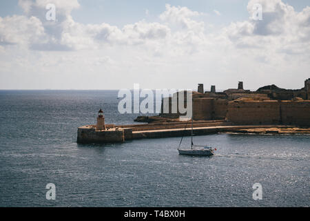 Blick auf den Grand Harbour Eingang und alte mittelalterliche Ricasoli Osten Wellenbrecher mit roter Leuchtturm und Fort Ricasoli von Valletta, Malta betrachtet Stockfoto