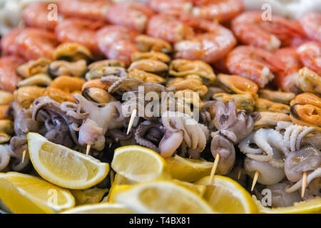 Köstliche Meeresfrüchte leckere Spieße von Kraken, Tintenfisch, Garnelen und Muscheln auf Holzstäbchen Nahaufnahme. Stockfoto