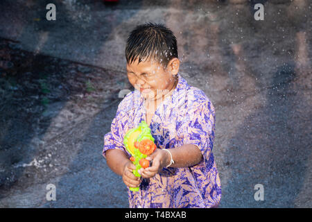 SUKHOTHAI, Thailand - 15 april 2019: Thai Kinder schiessen mit Wasserpistole während Neujahr Songkran Water Festival auf der Straße. Stockfoto