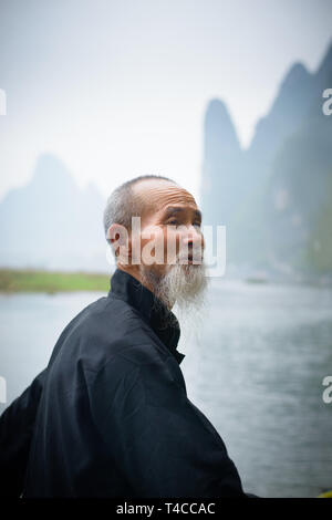 Portrait eines Flusses Lee Kormoran Fischer in der Dämmerung mit karst Gipfeln im Hintergrund. Guangxi Region von China. Stockfoto