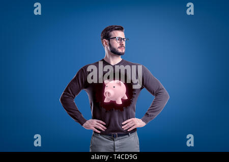 Mann mit Brille und ein rosa Sparschwein auf einem grauen Überbrückungsdraht auf blauem Hintergrund Stockfoto