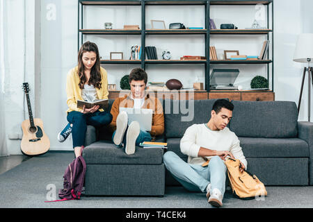 Drei multikulturellen Studenten mit Notebooks und Laptop studieren beim Sitzen auf dem Sofa Stockfoto