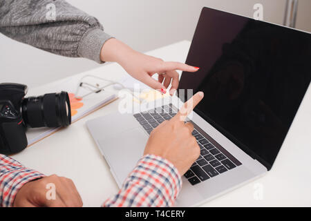 Zwei Fotografen mit Kamera und Laptop arbeiten im Büro Stockfoto