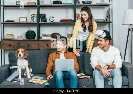 Drei Lachen multikulturellen Freunde mit Hund mit VR-Headset im Wohnzimmer Stockfoto