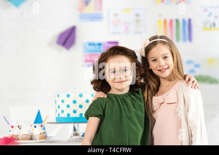 Adorable Kinder umarmen und die Kamera während der Geburtstagsfeier Stockfoto