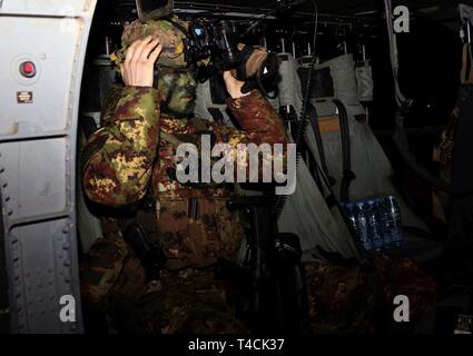 Italienische Armee Kapitän Lorenzo Mancini passt seine Advanced combat Helm (ACH) auf einem UH-60 Blackhawk in Vorbereitung auf eine Mission während der Übung bereit zu Kämpfen, 18. März an lielvarde Air Base, Lettland. Bereit zu kämpfen ist eine multinationale Übung, die die kollektive Verteidigung zeigt, wie die USA geschickt erreicht arbeitet zusammen mit Verbündeten und Partner Nationen. Beteiligung an multinationalen Übungen wie RTF entwickelt professionelle Beziehungen und verbessert die allgemeine Koordinierung mit Verbündeten und Partnern während der Krise. Stockfoto