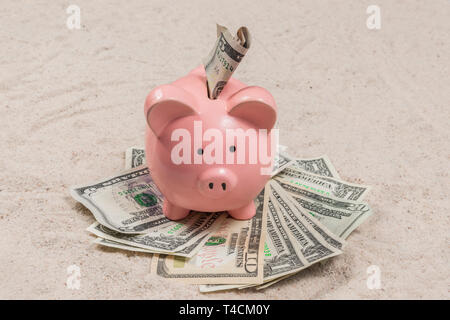 Horizontale geschossen von einem Sparschwein mit Bargeld an einem Sandstrand urlaub Strand. Stockfoto
