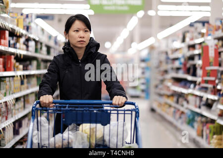 Asiatische Frau mit Warenkorb Sie Lebensmittel einkaufen im Supermarkt Stockfoto