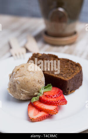 Kuchen, vegane Eis und Erdbeeren auf einem Holztisch Stockfoto