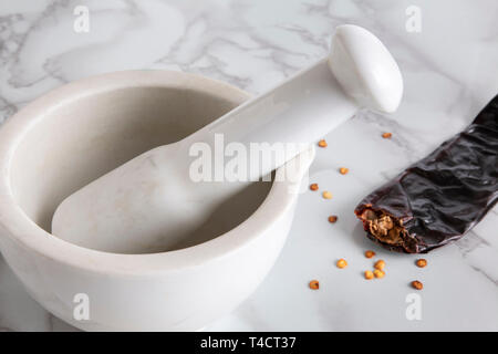 Nahaufnahme eines Stößel und Mörser neben einer getrockneten Paprika und Chili Samen Stockfoto