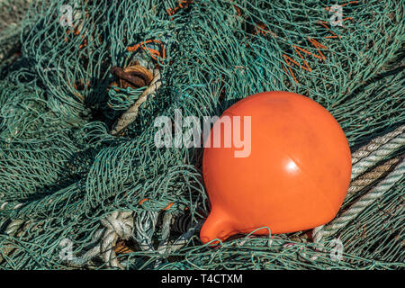 Eine verwirrte Fischernetz mit einer orange Angeln Boje auf der Oberseite. Stockfoto