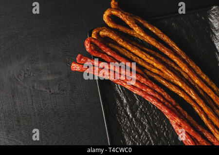 Polnische herkömmlichen Thin Würstchen kabanos auf schwarzem Hintergrund. Kopieren Sie Platz. Fett essen Konzept. Stockfoto