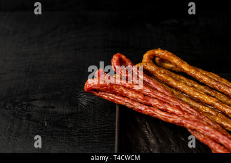 Polnische herkömmlichen Thin Würstchen kabanos auf schwarzem Hintergrund. Kopieren Sie Platz. Fett essen Konzept. Stockfoto