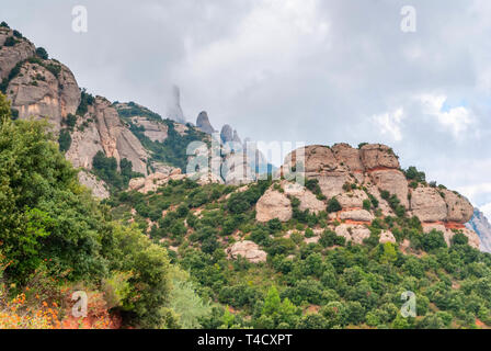 Hazy ungewöhnliche Berge mit grünen Bäumen und bewölkter Himmel in der Nähe von Kloster Montserrat, Spanien. Katalonien Stockfoto